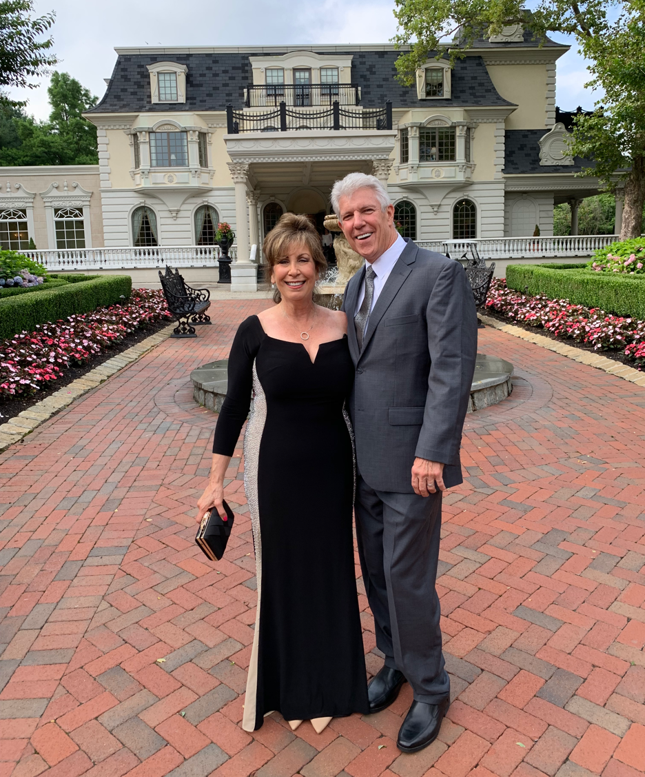 A person standing in front of a brick buildingDescription automatically generated